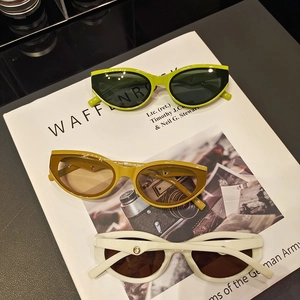 Vintage cat-eye sunglasses with thick frames and gold trim on stack of magazines