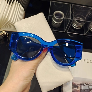 Detailed close-up of retro electric blue chunky frame sunglasses with a white leather pouch