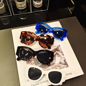 Retro thick frame sunglasses set in blue, black, and white on a fashion magazine