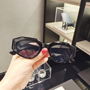 Detail shot of black hexagonal cat eye sunglasses with dark lenses and modern frame