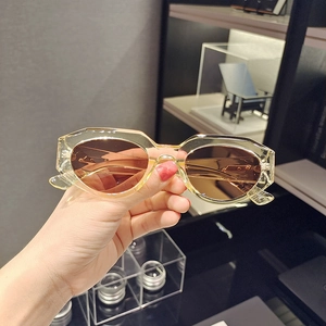 Detail view of cat eye sunglasses with translucent amber polygon frames and brown lenses
