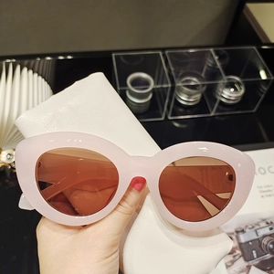 Détail de lunettes de soleil œil-de-chat roses avec un étui en cuir blanc grainé