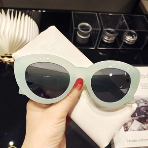 Détail de lunettes de soleil œil-de-chat vert menthe avec étui en cuir blanc et verres foncés