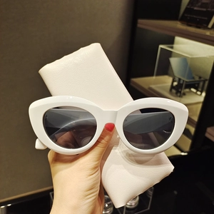 Gros plan de lunettes œil de chat blanches avec verres gris et pochette rose