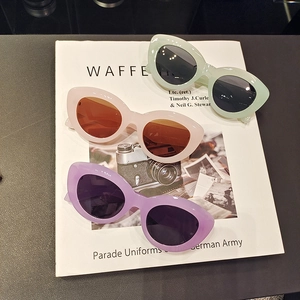 Lunettes de soleil œil-de-chat élégantes en vert pastel, rose et violet sur un magazine