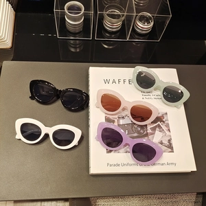 Lunettes de soleil œil-de-chat en cinq couleurs dont des tons pastels sur un magazine