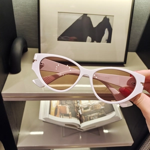 Detailed view of cat-eye sunglasses with white frame and gold temple accents