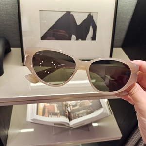 Close-up of translucent grey cat-eye sunglasses with gold metal arrow hinges