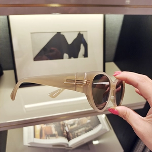 Detail of champagne oversized sunglasses with gold metal hinges and dark tinted lenses