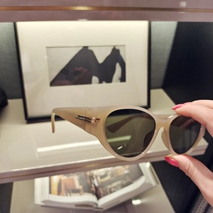 Detail of nude cat-eye sunglasses with signature gold metal hinges and dark lenses