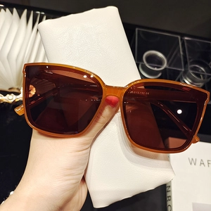 Detail of amber tortoiseshell sunglasses with dark lenses and a white leather case