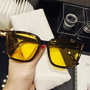Detail of square sunglasses with yellow lenses and premium white leather pouch case