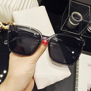 Close-up of oversized black sunglasses with a textured white leather storage pouch