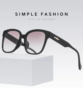 Détail de lunettes de soleil carrées noires avec touches dorées et verres dégradés