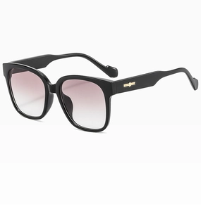 Détail de lunettes de soleil larges avec verres dégradés rose-gris et accents dorés