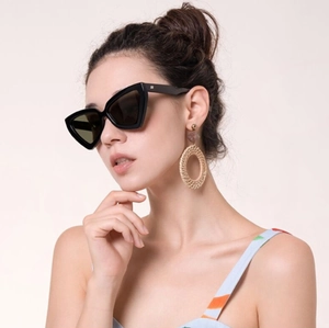 Détails de lunettes de soleil œil-de-chat noires et boucles d'oreilles sur un mannequin