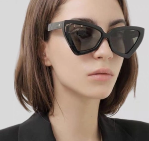 Vue latérale de lunettes de soleil œil-de-chat noires avec branches larges et logo en métal