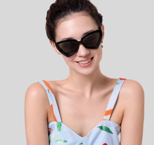 Lunettes de soleil œil de chat triangulaires noires portées par un mannequin en studio