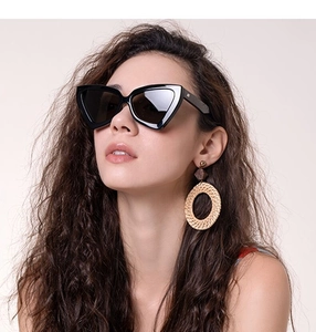 Détail de lunettes de soleil œil de chat noires et boucles d'oreilles bohèmes sur modèle