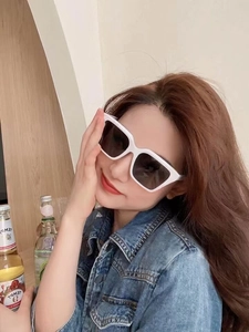 Close-up of white square frame sunglasses with black lenses on a model in denim