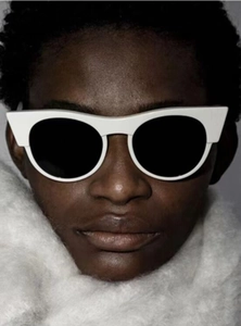 Detail of vintage cat-eye sunglasses with thick white frames and dark lenses on model