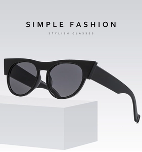Detail view of thick black geometric frame cat-eye sunglasses on a white podium