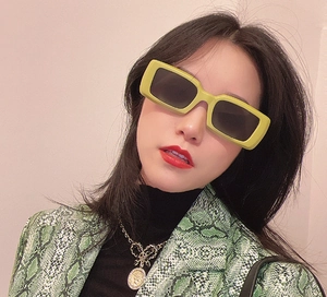 Detail of yellow rectangular sunglasses paired with a green snakeskin print jacket