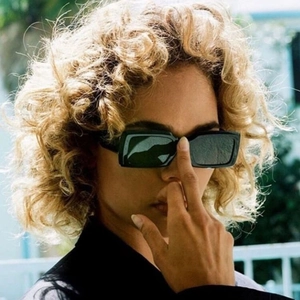 Close-up of model wearing black rectangular sunglasses with minimalist dark lenses