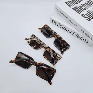 Three pairs of vintage rectangle sunglasses in tortoiseshell patterns on white books