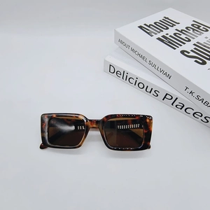 Detail view of tortoiseshell rectangle sunglasses with dark lenses on minimalist books