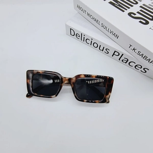 Flat lay of vintage tortoise shell sunglasses with rectangle frames on minimalist books