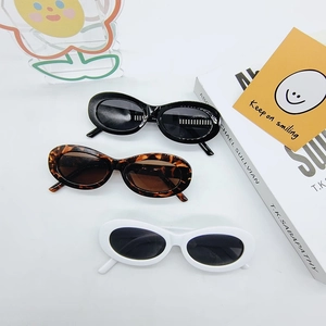 Flat lay of oval sunglasses in black, leopard, and white frames with a retro style