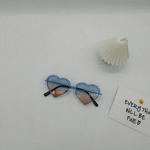 Détail de lunettes de soleil cœur pour enfants avec bords fleuris et verres dégradés bleu-rose