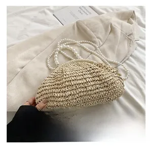 Détail d'un sac coquillage en paille tressée avec poignées en perles et texture fine