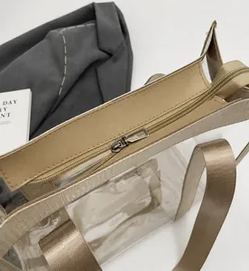 Dettaglio della cerniera in metallo e del manico in nylon kaki sulla borsa trasparente