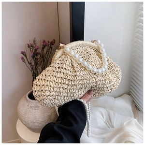 Détail du sac en paille tressée beige avec poignée et bandoulière en perles élégantes