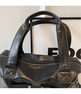 Detail of black pebbled leather tote bag with silver rivets and smooth zipper closure