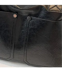 Close-up of black wrinkled leather tote bag with silver studs and quilted edge detail