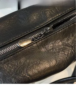 Detail of smooth gunmetal hardware zipper pull on black textured leather tote bag