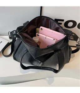 Close-up of black retro tote bag interior showing spacious capacity with a tablet and bottle