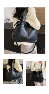 Detail of black faux leather tote bag showing lychee texture and metallic rivet accents