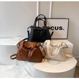 Detailed display of large retro tote bags in black, brown and cream with metal rivets