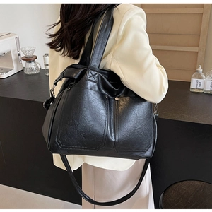 Rear view of a model wearing a black vintage PU leather tote bag with dual front pockets