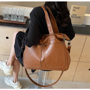 Brown vintage faux leather tote bag with front pockets shown on a shoulder model