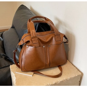 Detailed view of caramel brown tote bag with utility pockets and metallic rivet accents