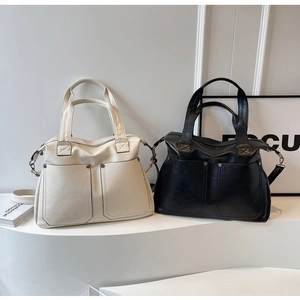 Detail view of large tote bags with front pockets and metallic rivets in black and cream