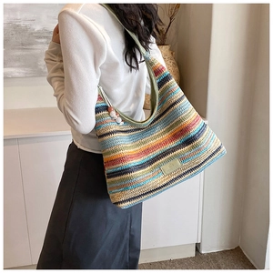Detail of colorful striped woven tote bag featuring beaded charm and leather logo patch