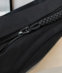 Detailed close-up of smooth black hardware zipper pull and braided cord on a nylon bag