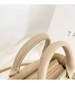Détail du sac à main crème montrant les coutures fines et la fermeture éclair dorée