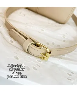 Détail de la bandoulière en cuir beige avec boucle réglable dorée et coutures fines